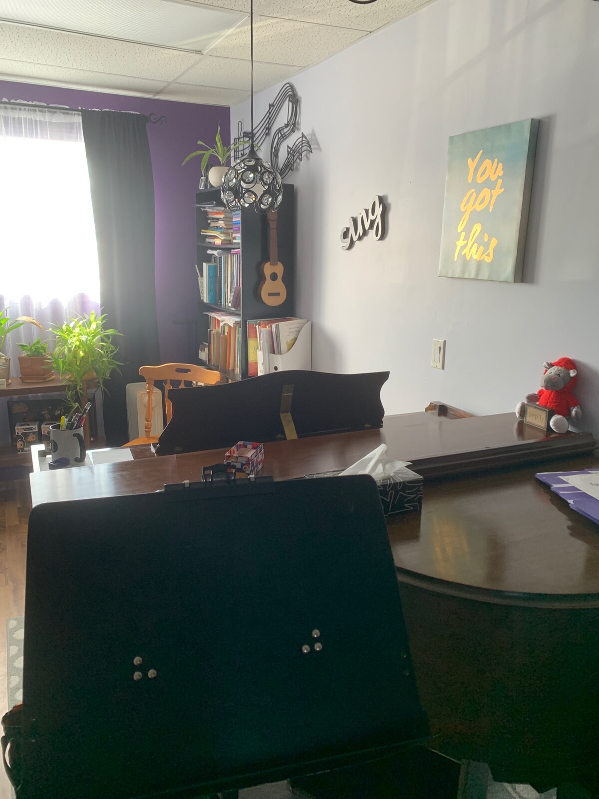 The Alexandria studio seen from the piano: a purple wall, plants in the window, and a ukulele on the bookcase.