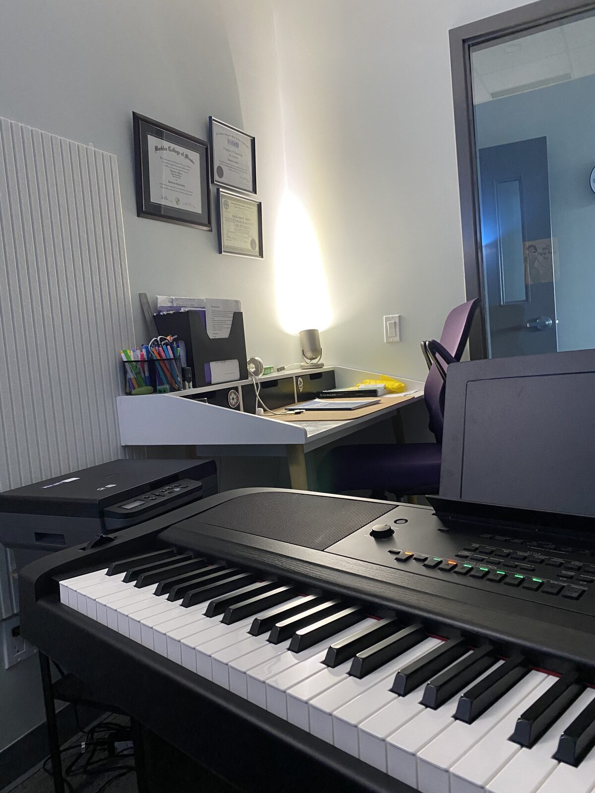 The piano keys, with Katie’s framed diplomas and her desk behind.